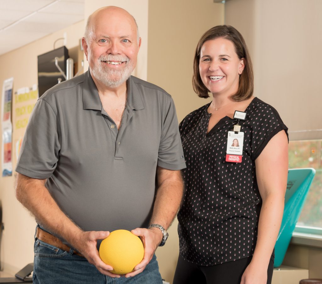 Colan Ratliff holding a medicine ball with Physical Therapist Beth Ann Galligan